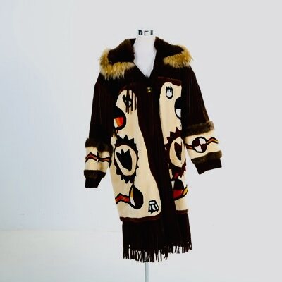 Fringed hide coat with painted cream panels, fur collar and a medicine-wheel sleeve, on a white dress form.