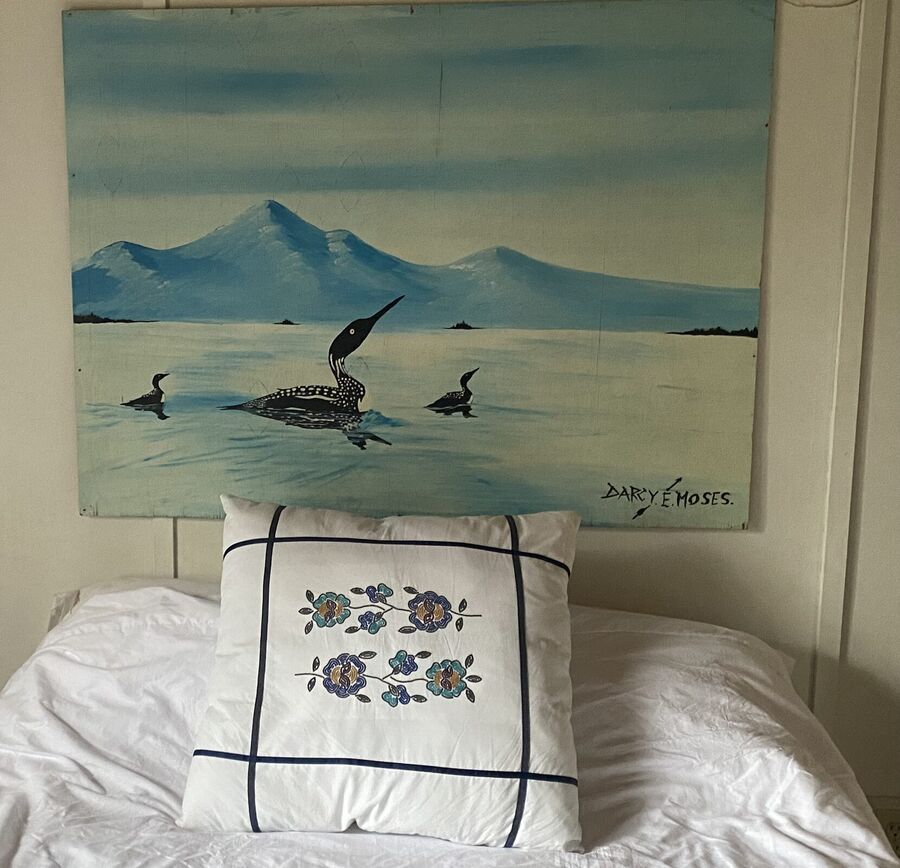 White embroidered pillow, loons on the wall