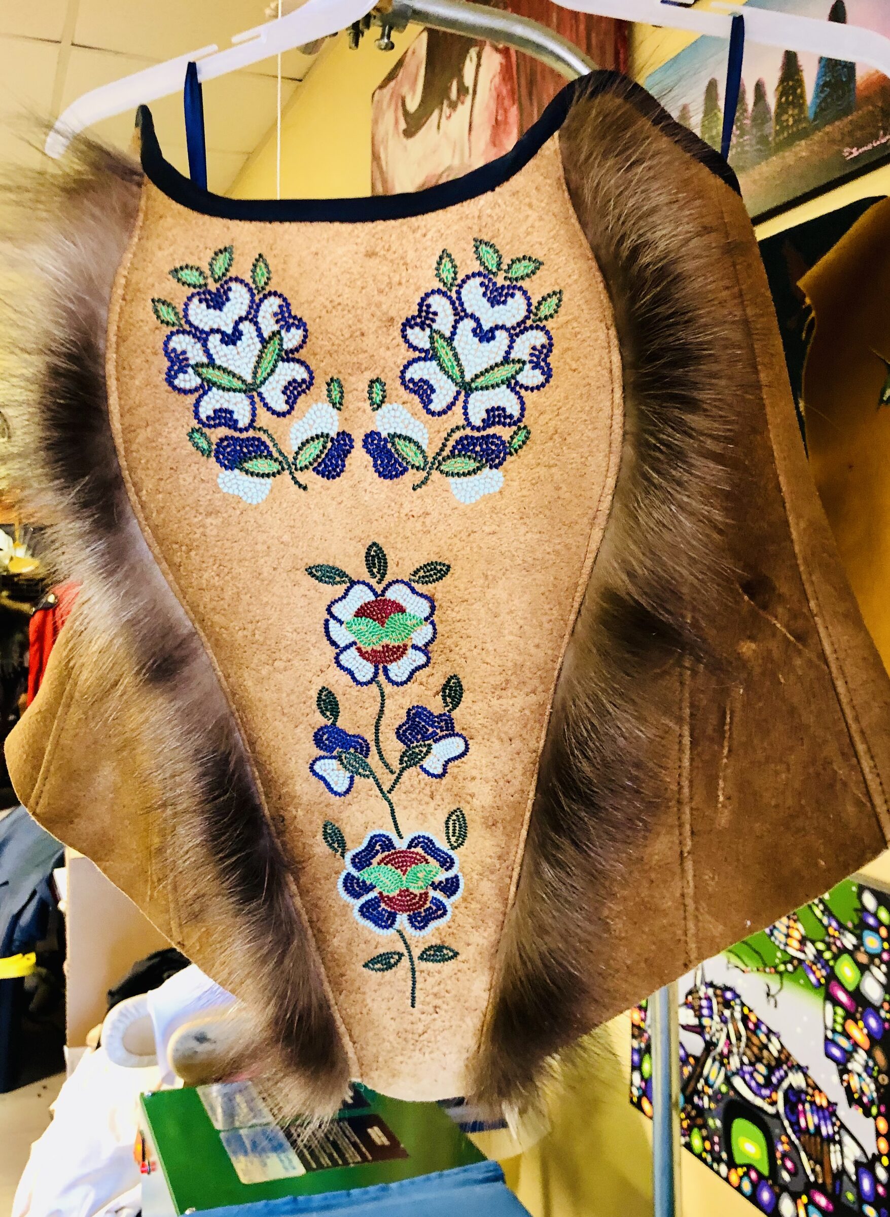 Tan moosehide vest panel with floral seed-bead work and dark fur trim.